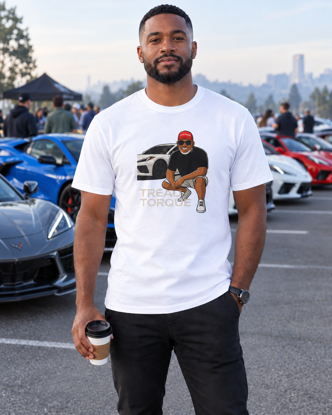 Man in a black C8 Matrix tee showing a silver Corvette C8 front-end graphic, standing in a garage beside a silver Corvette